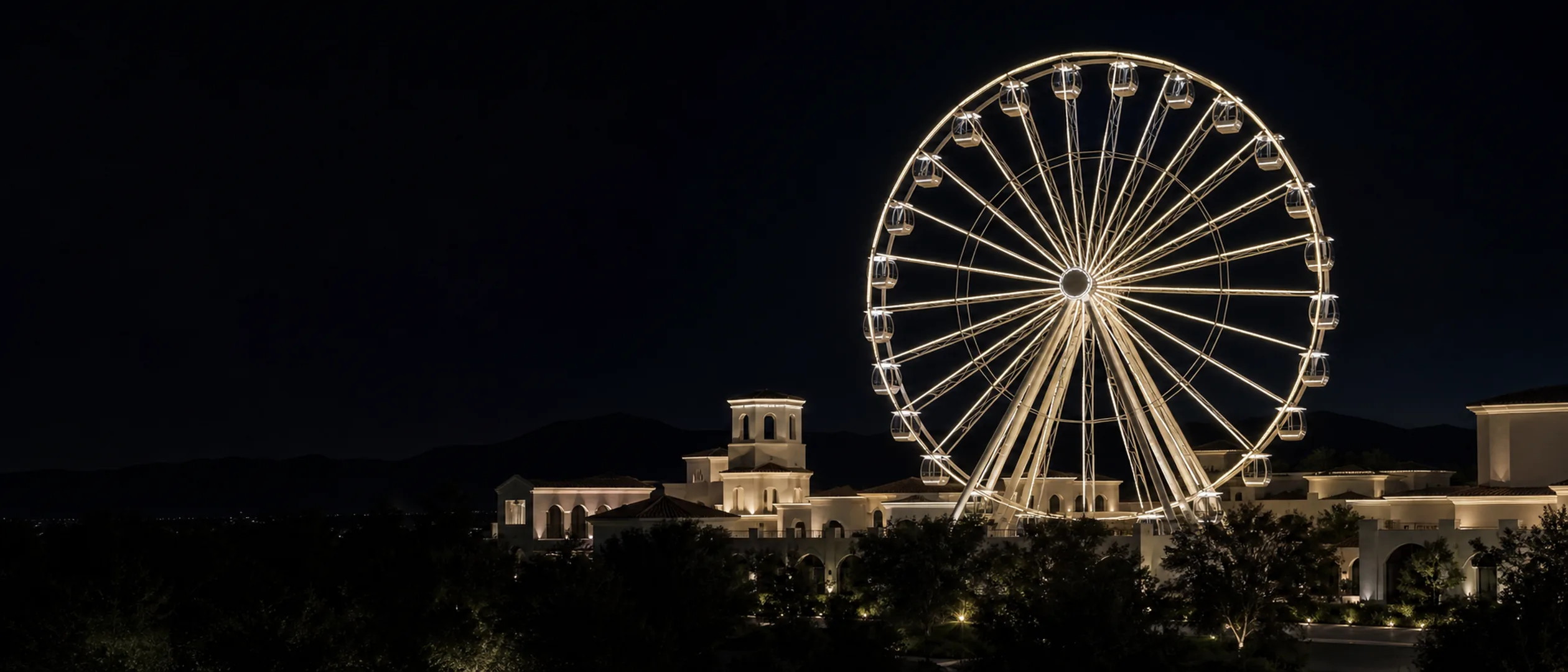 The Irvine Spectrum Giant Wheel and low Spanish-style buildings glow at blue hour beneath the San Joaquin Hills.