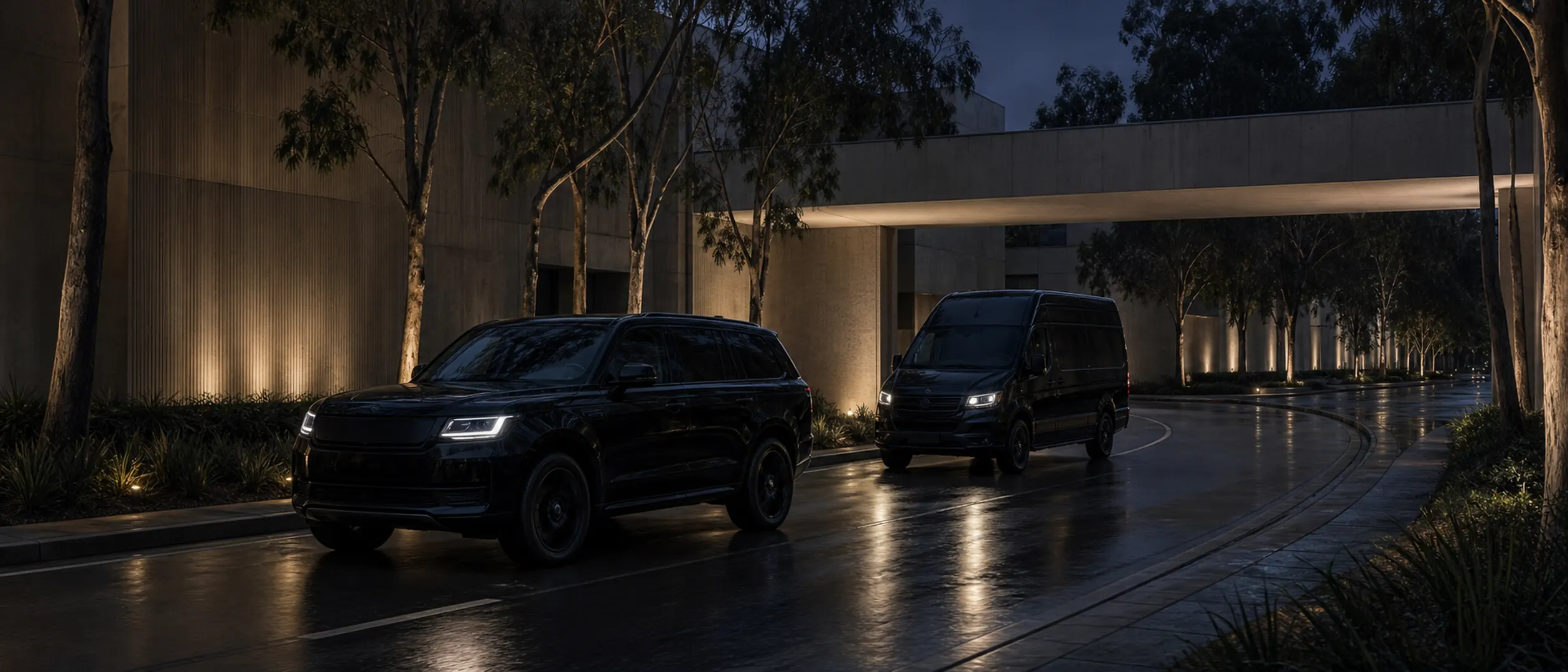 A near-black SUV leads an executive van along a eucalyptus-lined road at UCI.